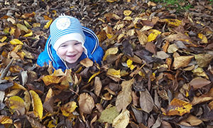 Kleiner junge spielt in Laubhaufen. (Herbststimmung)